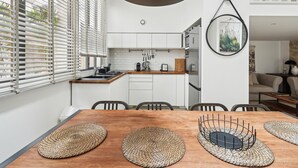A modern kitchen with white cabinets, a wooden countertop, and a hanging pendant light.