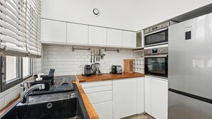 A modern kitchen with white cabinets, a stainless steel refrigerator, and a built-in oven.