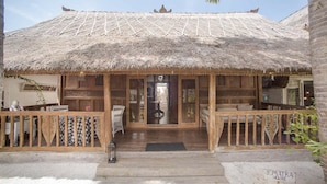 A thatched-roof building with a wooden deck and a sign reading "SUMATRA HOUSE".