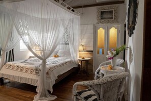 A bedroom with a four-poster bed, a bedside table with a lamp, and a decorative vase with flowers.