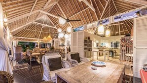 A spacious, open-plan interior with a high, wooden ceiling and wicker furniture.