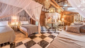 A spacious bedroom with two beds, a checkered floor, and a high ceiling with wooden beams.