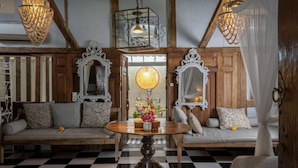 A room with a checkered floor, wooden furniture, ornate mirrors, and hanging light fixtures.