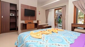Una habitación de hotel con cama, televisión montada en la pared, escritorio y armario.
