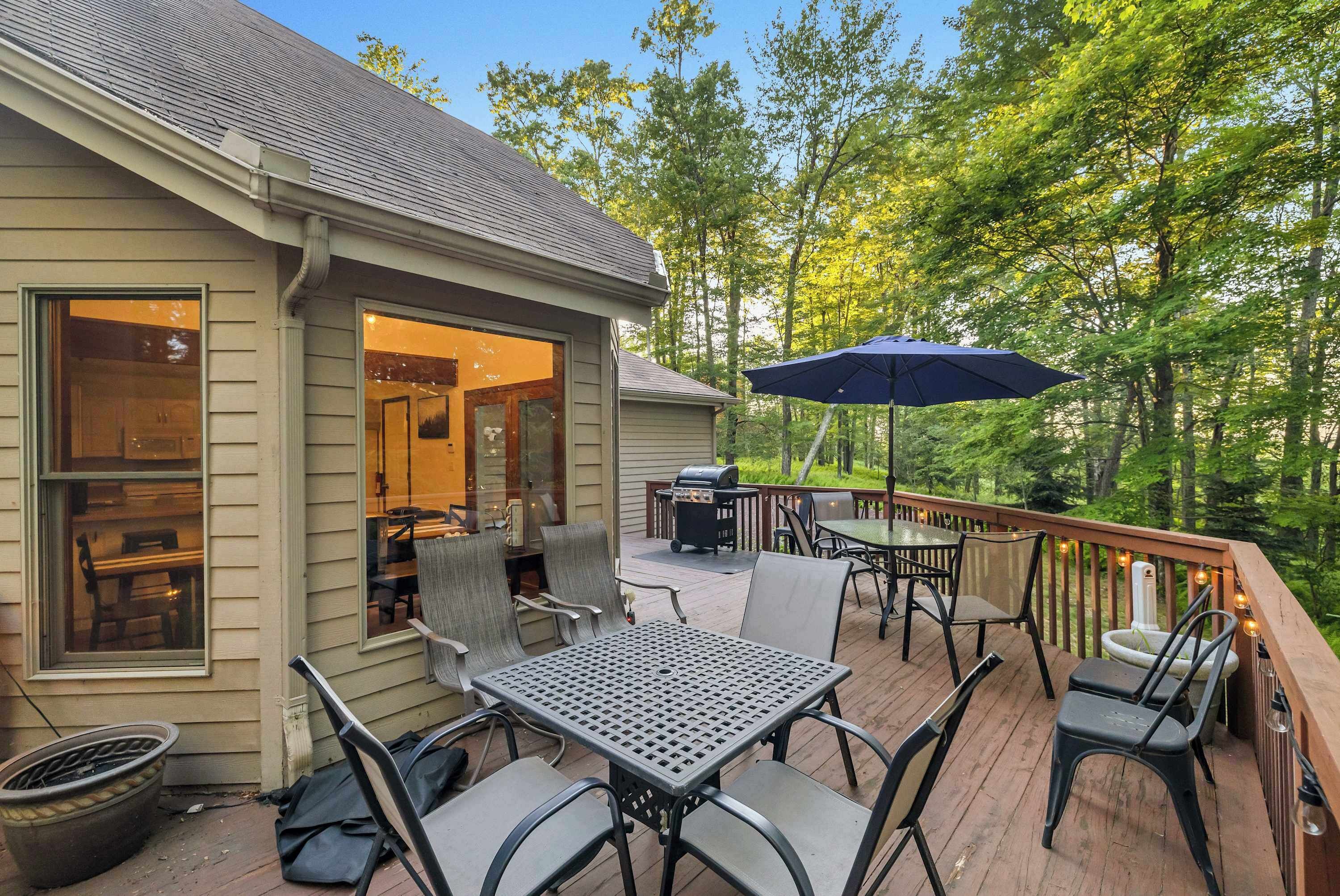 An outdoor deck with a table and chairs, a grill, and a patio umbrella.