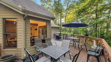 An outdoor deck with a table and chairs, a grill, and a patio umbrella.