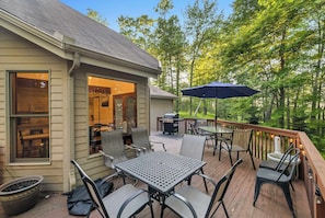 An outdoor deck with a table and chairs, a grill, and a patio umbrella.