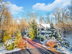Paesaggio innevato con una casa, alberi e cielo sereno.