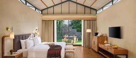 Un dormitorio con una cama grande, mesitas de noche, un escritorio, un televisor y vistas al exterior.