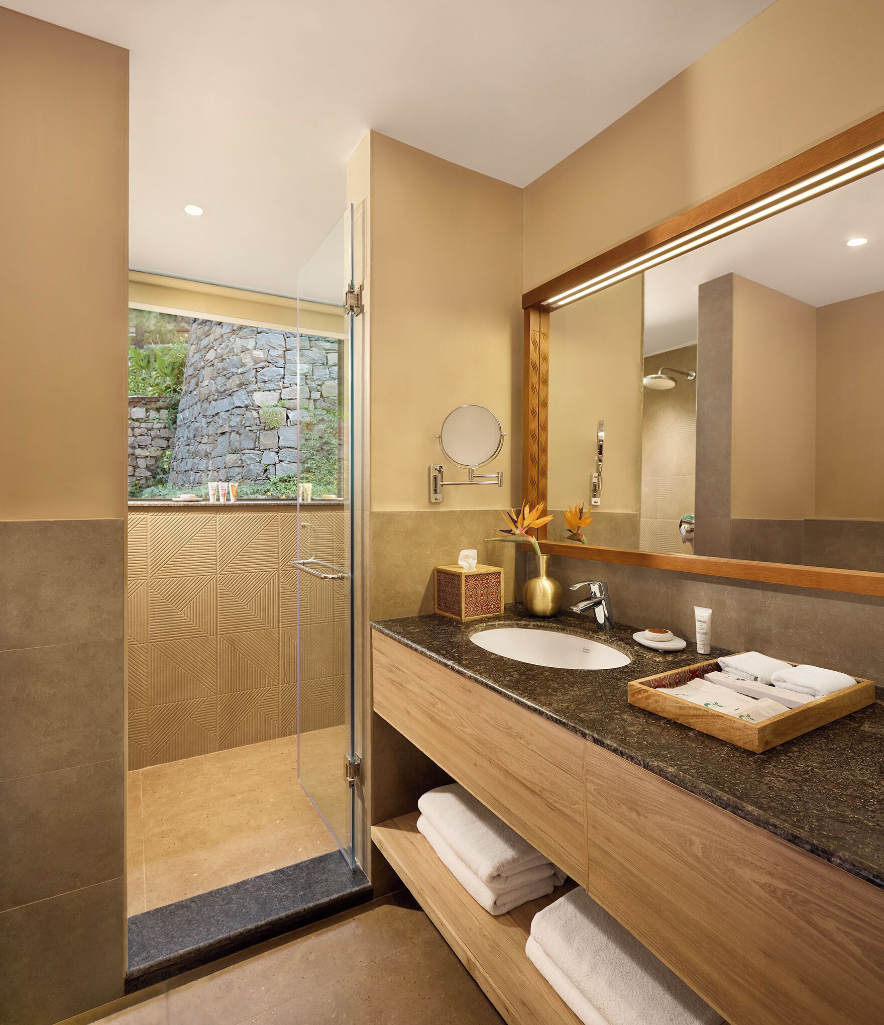 A modern bathroom with a large mirror, granite countertop, and a shower with a glass door.