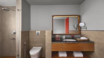 A modern bathroom with a shower, toilet, vanity with a mirror, and a sink.