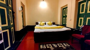Una habitación con cama, alfombra roja y puertas verdes.