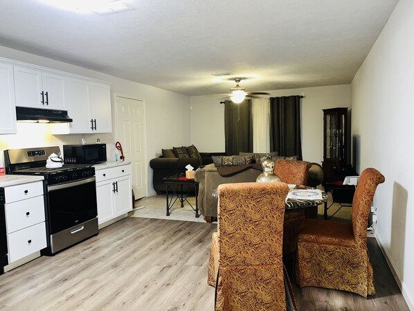 A compact living space with a kitchenette, a dining area, and a seating area with patterned chairs.