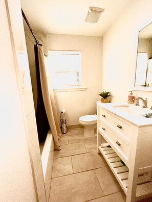 A small bathroom with a toilet, sink, and shower.