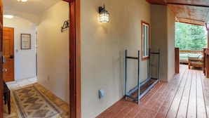 Une véranda en bois offrant une vue sur un paysage verdoyant, une porte dotée d’une serrure de sécurité, un luminaire fixé au mur et une citation encadrée accrochée au mur.