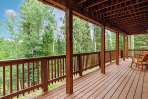 A wooden deck with a railing, overlooking a forested area. - Moonlight Pines by Velo (Angel Fire)