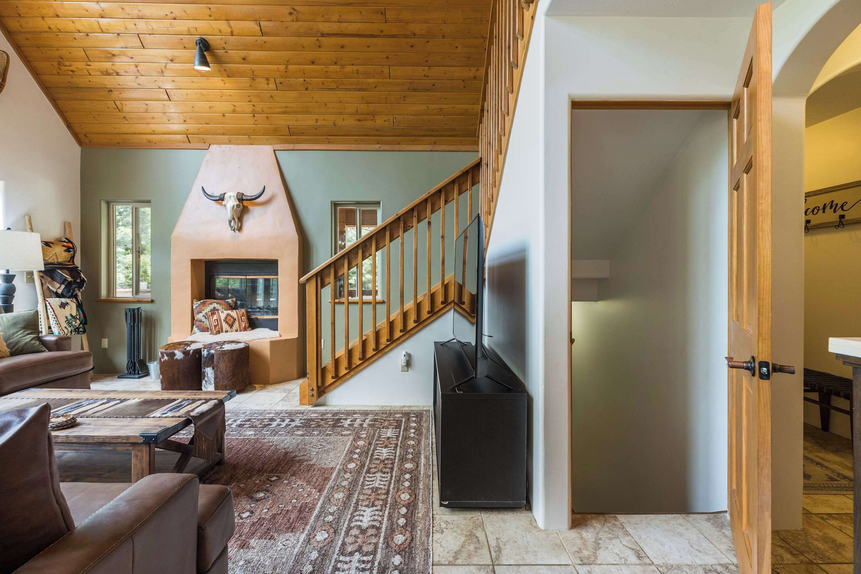 A living room with a fireplace, a staircase, and a television.