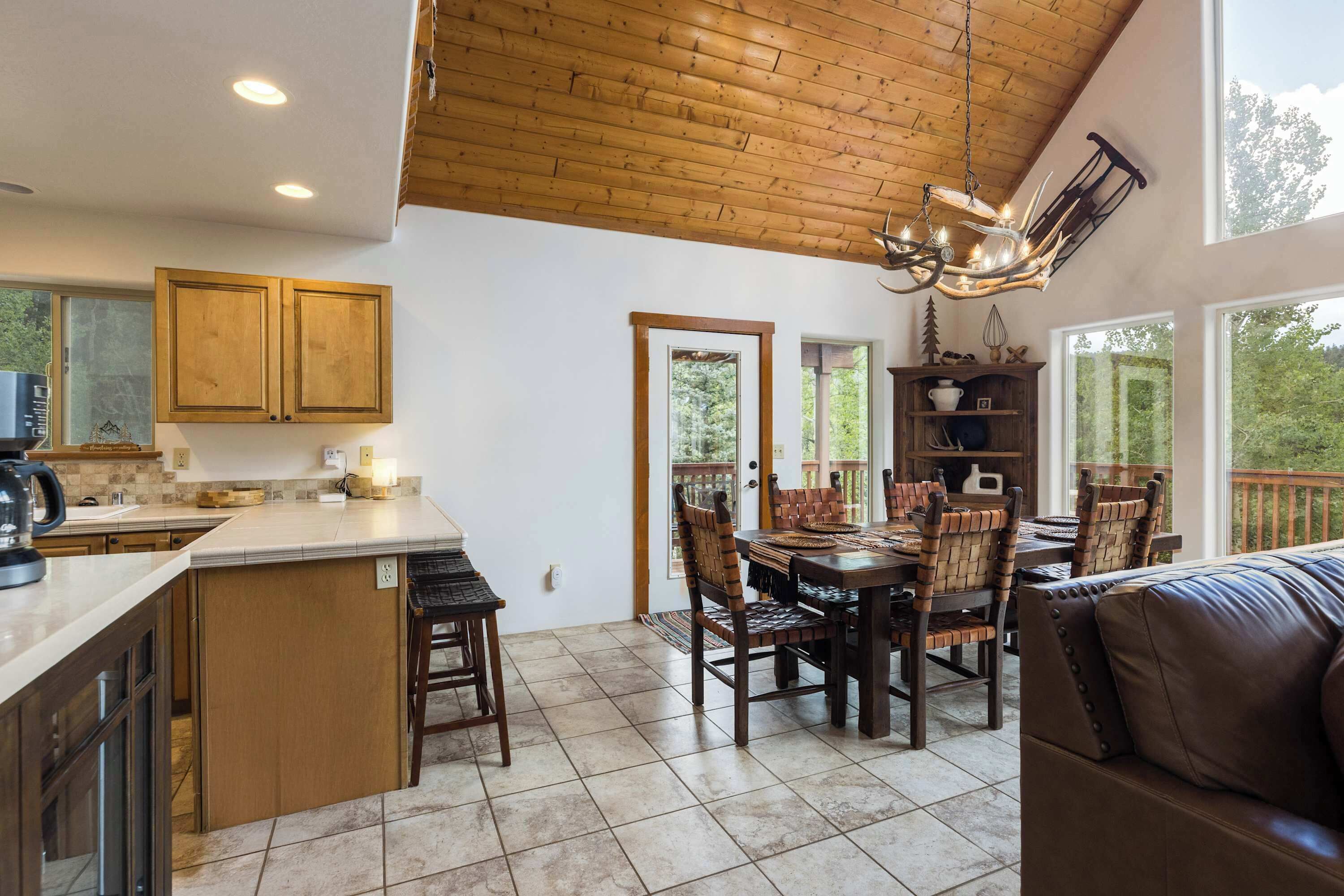 A spacious kitchen with wooden cabinets, a dining area with a large table and chairs, and a view through the windows.