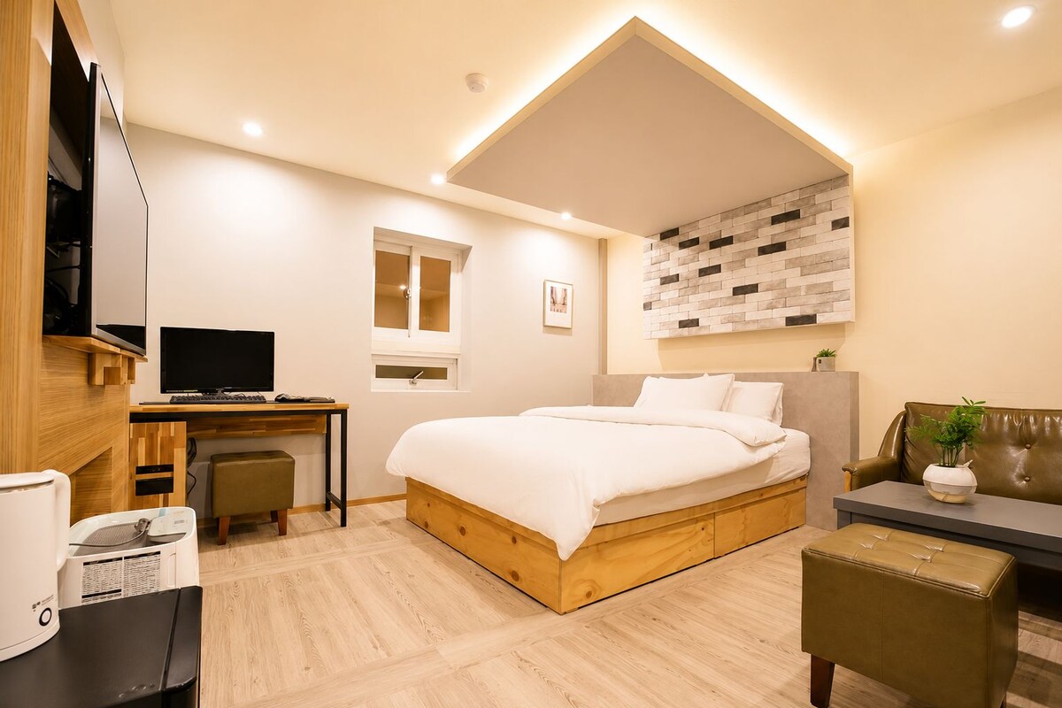 Un dormitorio moderno con cama, escritorio y zona de estar.