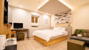 Ein modernes Schlafzimmer mit Bett, Schreibtisch und Sitzgelegenheit.