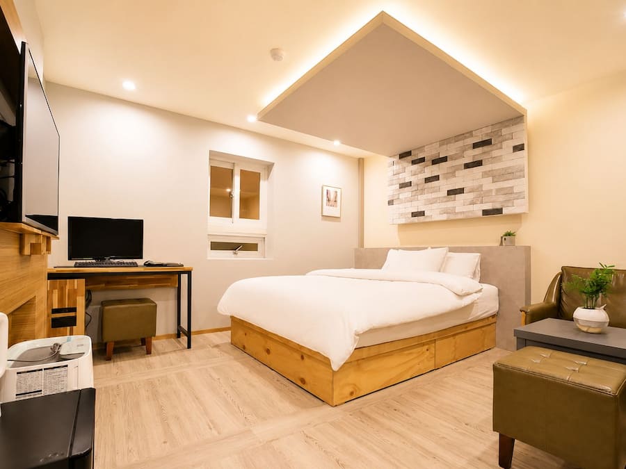 Un dormitorio moderno con cama, escritorio y zona de estar.