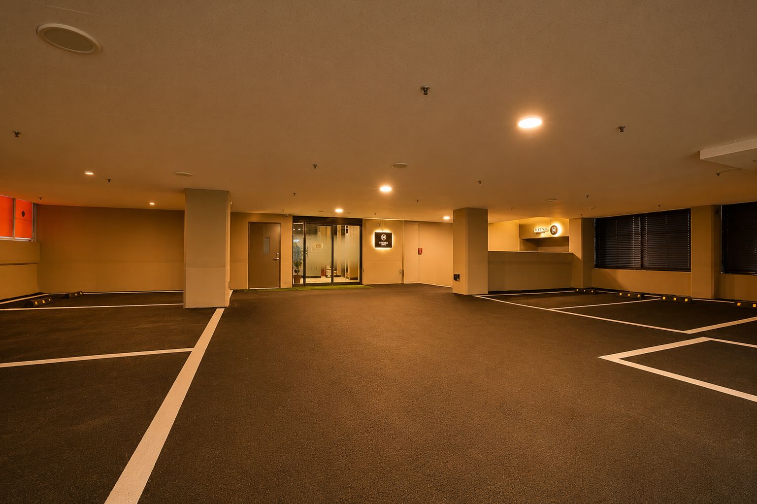 A parking garage with multiple parking spaces, a reception area, and a sign indicating a hotel.