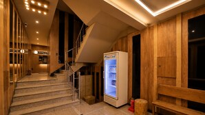 Vestíbulo de hotel con una escalera, un refrigerador Star Cool y paneles de madera.