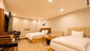 Habitación de hotel con dos camas, un escritorio y un televisor.