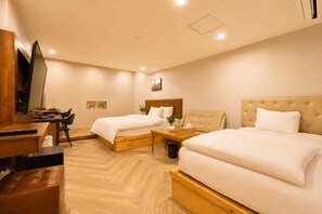 Habitación de hotel con dos camas, un escritorio y un televisor.