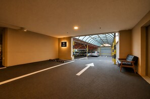 A parking garage with a clear path marked by arrows, a seating area with a bench, and a sign for 'HYUNDAI' on the wall. - Evian Hotel (Gyeongsan)