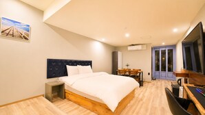 Una habitación de hotel moderna con una cama grande, un escritorio, una silla y un televisor.