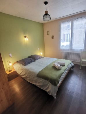 Ein Schlafzimmer mit Bett, Nachttischlampen, einem Heizkörper und einem Fenster.