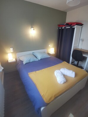 Ein Hotelzimmer mit einem Bett, zwei Nachttischlampen, einem Schreibtisch mit Stuhl und einem Vorhang.