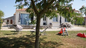 Une maison avec un toit en tuiles, une grande fenêtre et un arbre au premier plan.