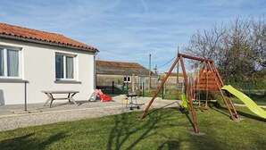 Un quartier résidentiel avec une maison, une balançoire et une table de pique-nique.
