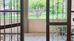 Une pièce donnant sur un jardin, avec une fenêtre ornée de barreaux en métal.