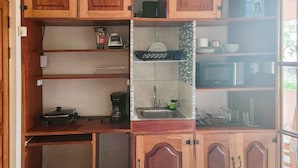 Une cuisine compacte dotée de meubles en bois, d’un four à micro-ondes, d’une machine à café et d’un évier.