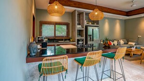 Une cuisine moderne dotée d’un îlot central, de tabourets de bar et de luminaires suspendus.