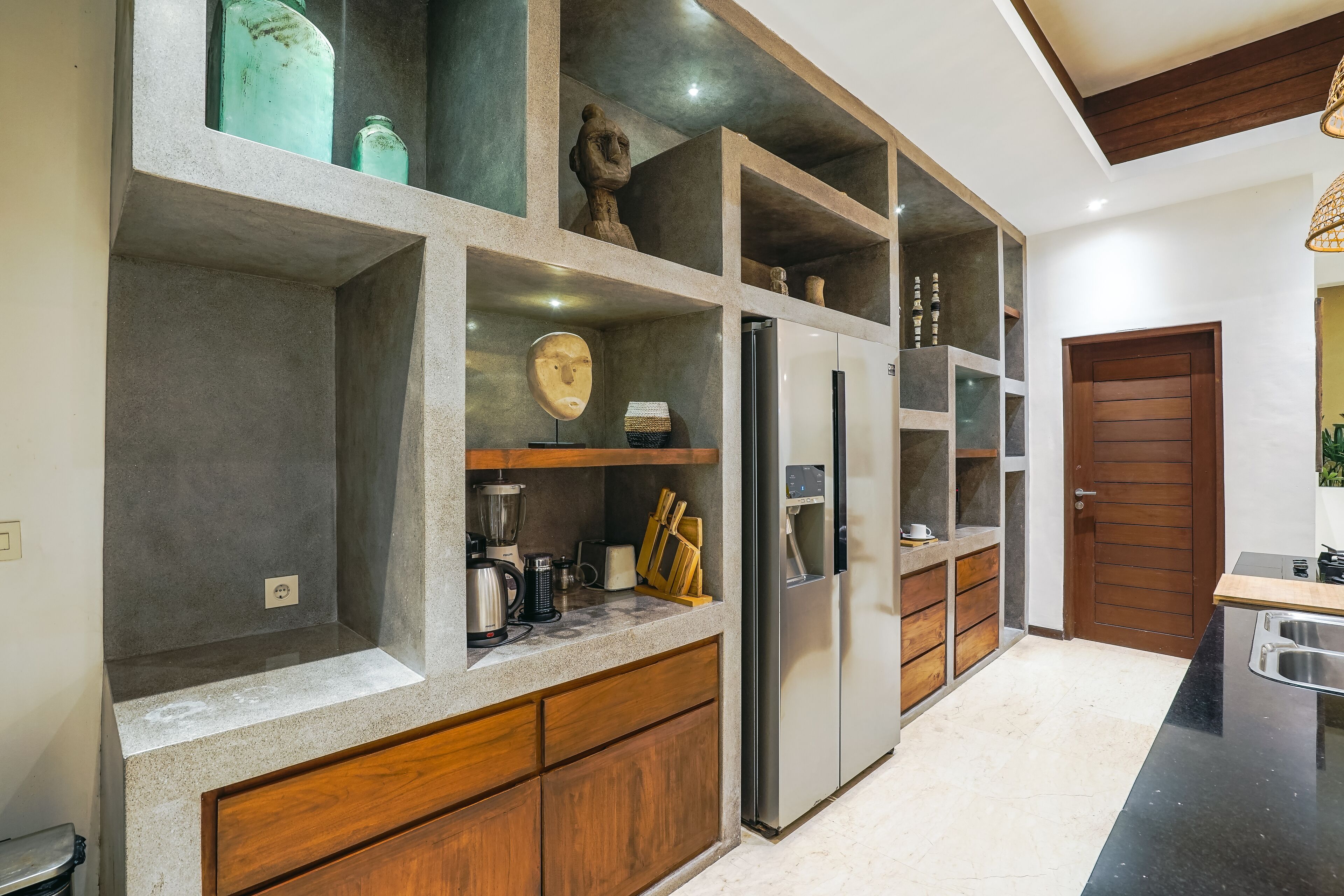 A modern kitchen with built-in cabinets, a stainless steel refrigerator, and a wooden countertop.