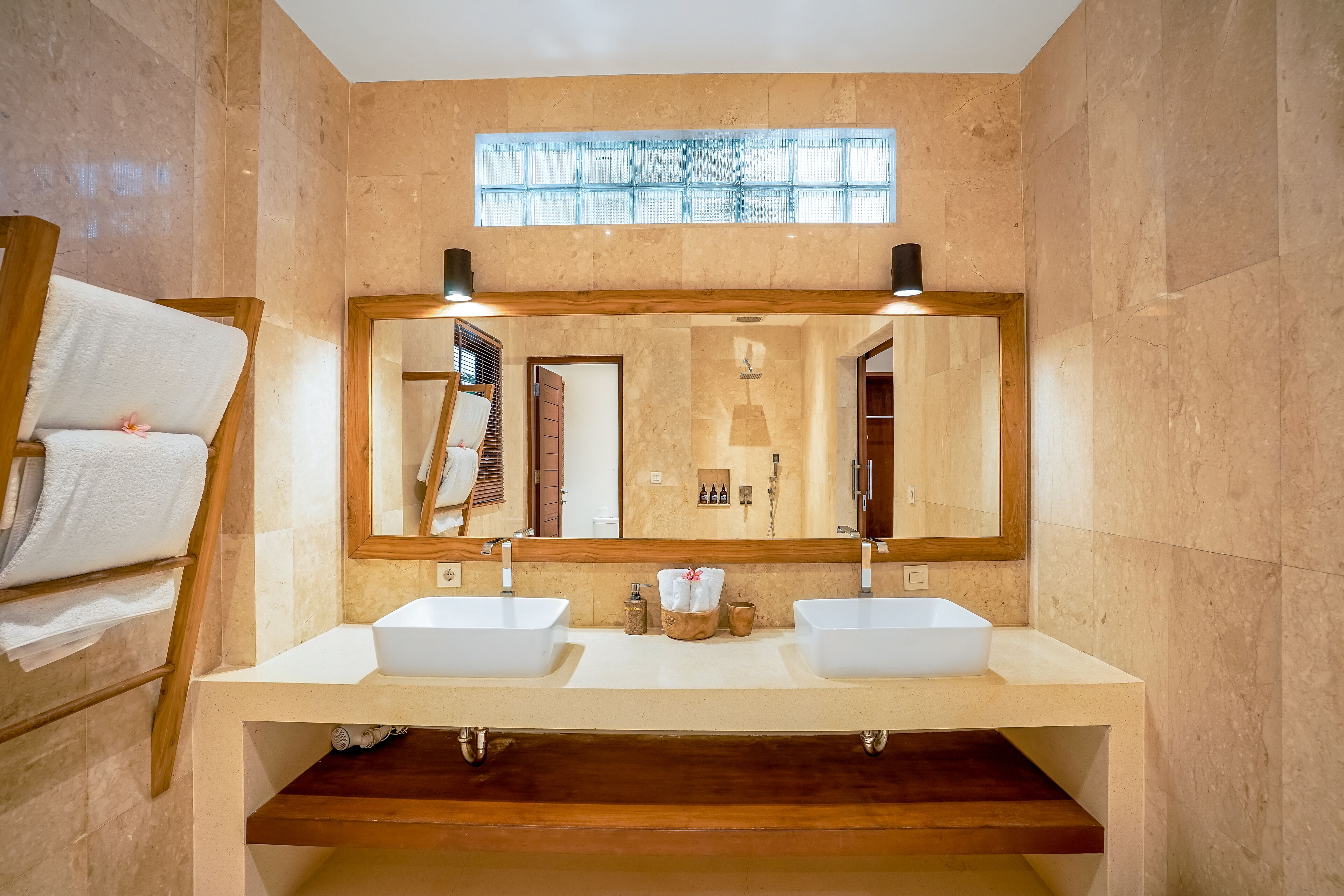 Un baño moderno con dos lavamanos, un espejo grande y un perchero para toallas.