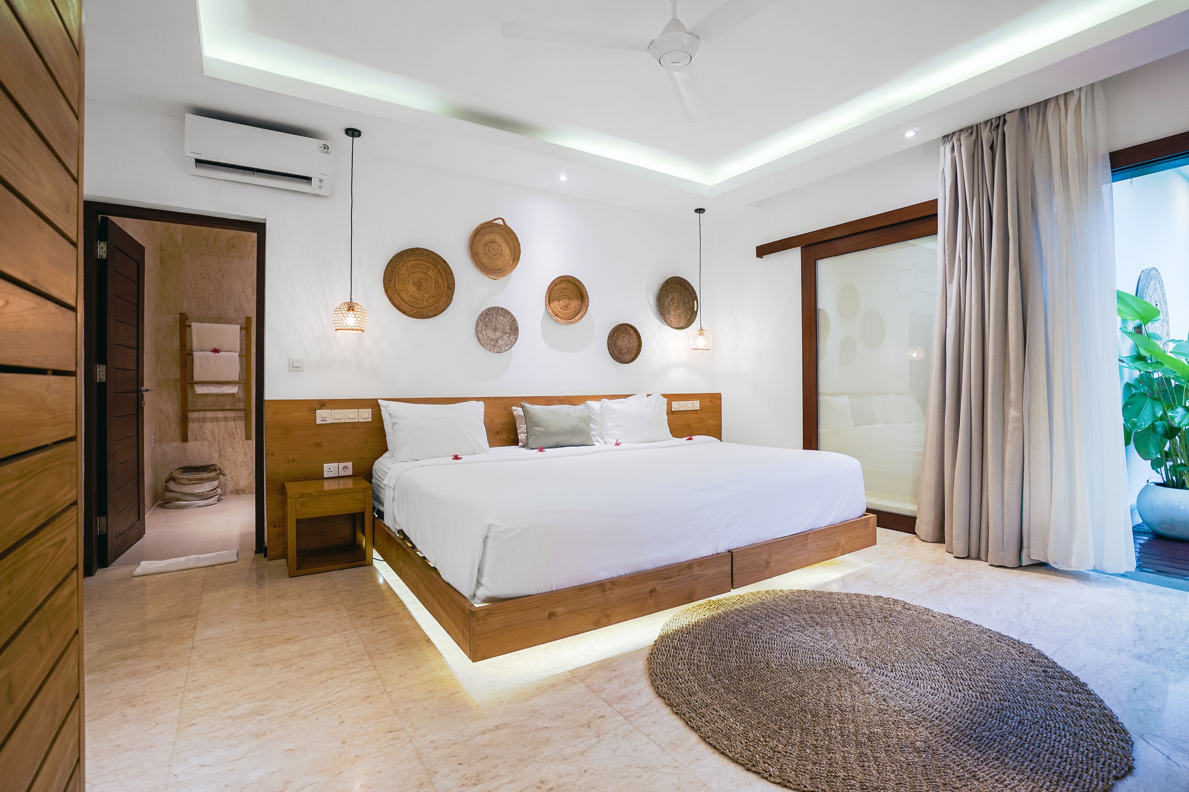 Un dormitorio moderno con una cama grande, cabecera de madera y ventilador de techo.