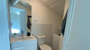 Une petite salle de bain comprenant des toilettes, un lavabo et un miroir.