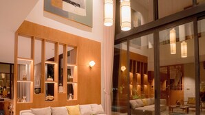 A modern living room with a sectional sofa, a coffee table, and a glass partition. - Icity Oneriver Luxury Villa (Da Nang)