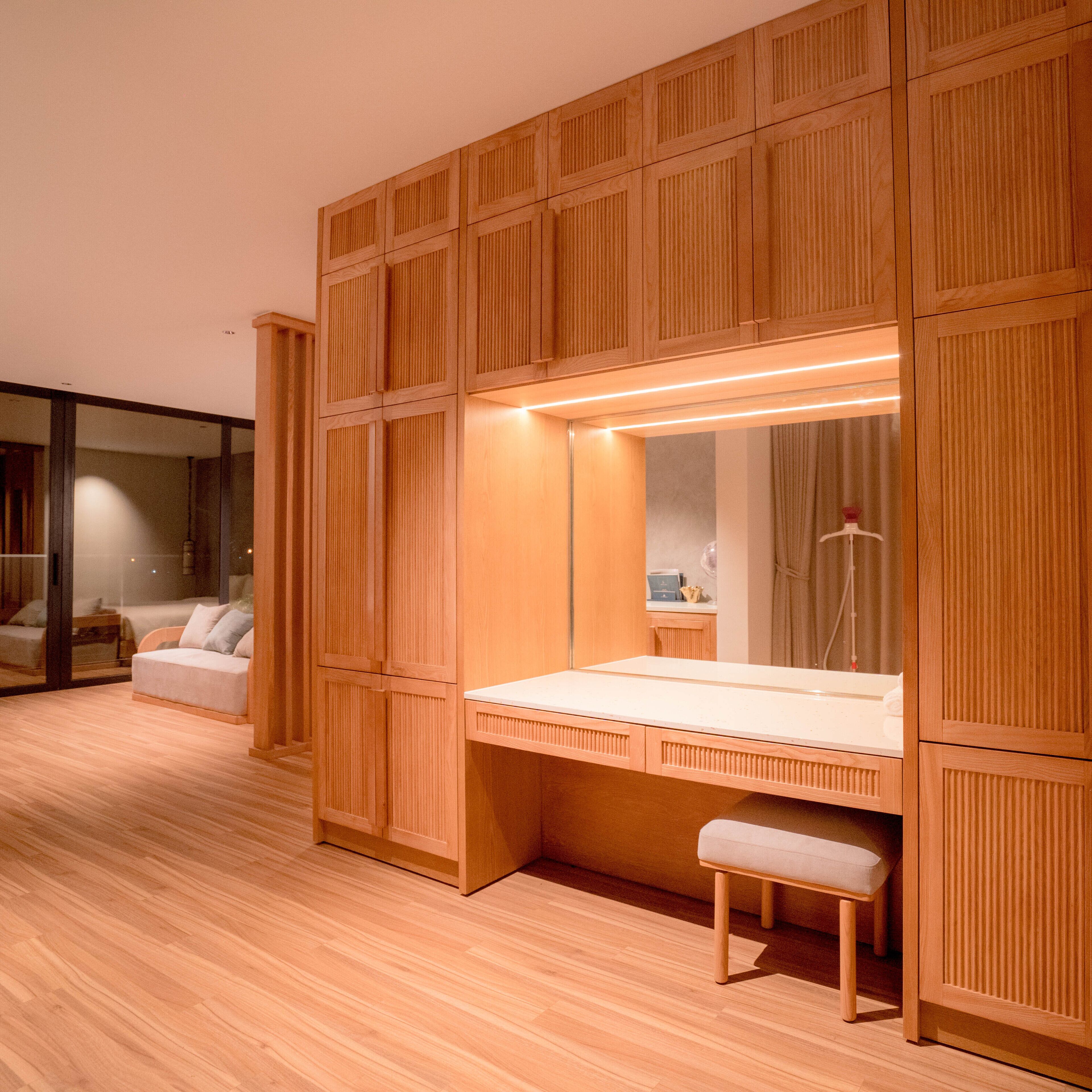 Ein modernes Zimmer mit Holzvertäfelung, einem großen Spiegel, einem Nachttisch und einer Bank.
