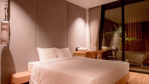 A modern hotel room with a large bed, a wooden nightstand, a small table, and a large window with curtains. - Icity Oneriver Luxury Villa (Da Nang)