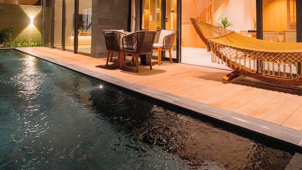 A modern outdoor pool area with a hammock, chairs, and a staircase leading to an upper level. - Icity Oneriver Luxury Villa (Da Nang)