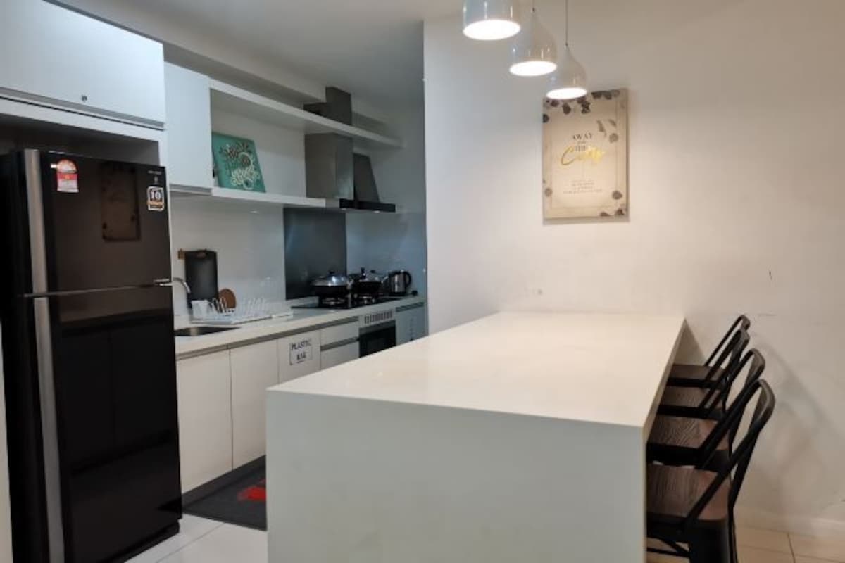 Una cocina moderna con un refrigerador negro, armarios blancos, una encimera blanca y un comedor con sillas.