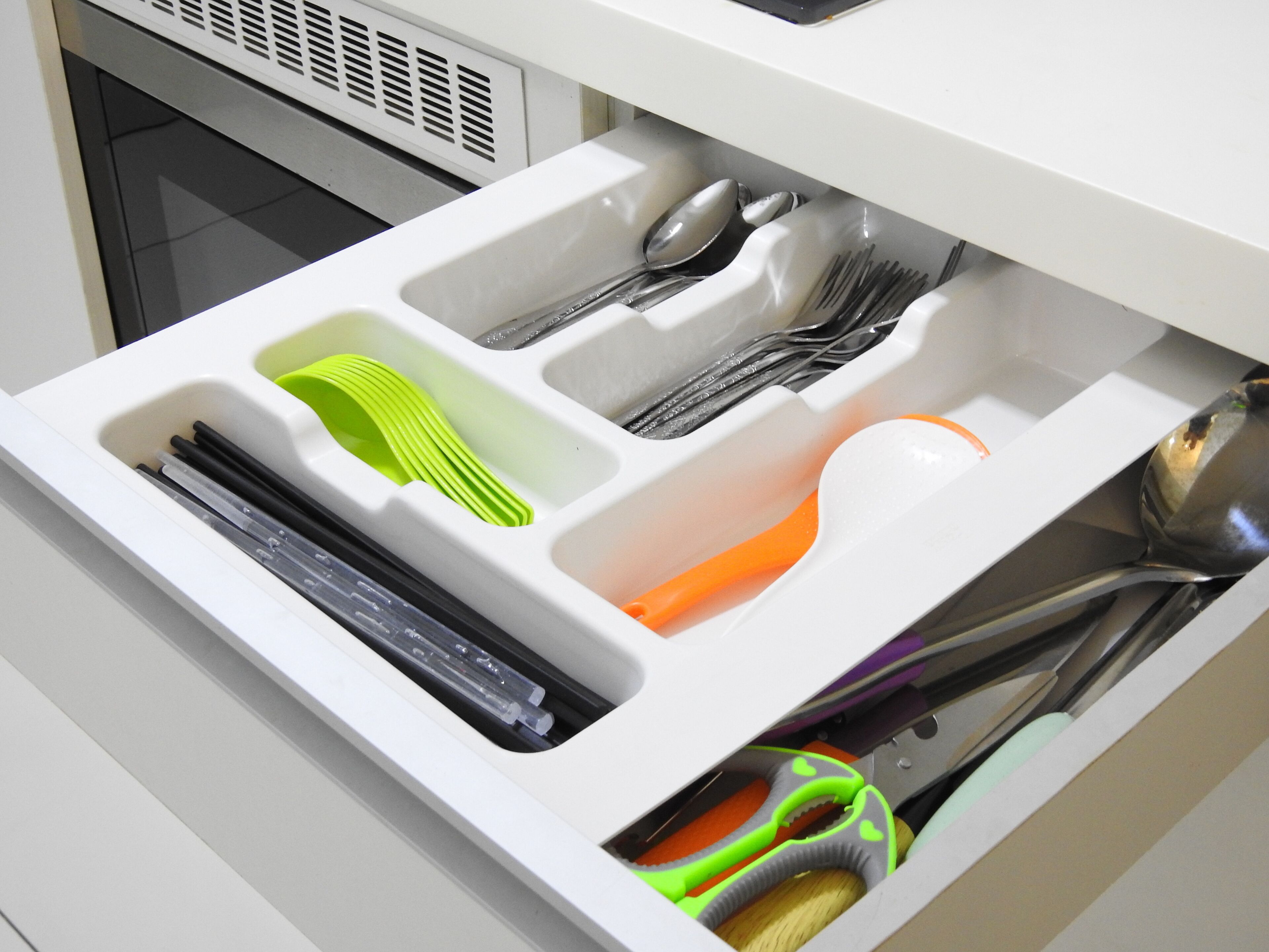 Un cajón de cocina con utensilios y batería de cocina organizados en compartimentos.
