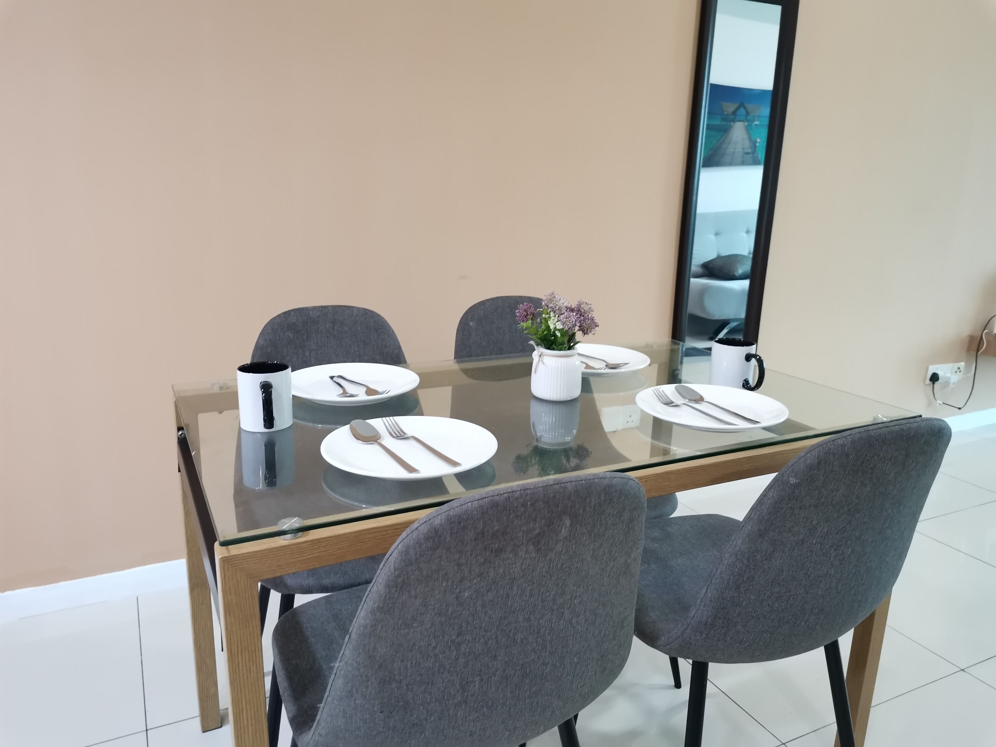 A dining table with four chairs, a vase with flowers, and a coffee maker.