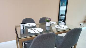 A dining table with four chairs, a vase with flowers, and a coffee maker.